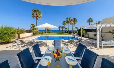 a table and chairs in front of a swimming pool at Royal Beachfront Villa in Protaras