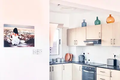 a kitchen with white cabinets and a picture of a woman at Nissini Shell, 3 bedroom villa with private pool at Nissi Beach in Ayia Napa
