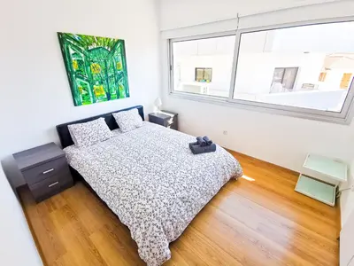 a bedroom with a bed and a large window at Daze Off Central Apartment, 300m to the Finikoudes Beach in Larnaka