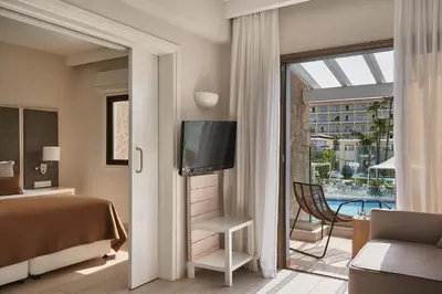a hotel room with a bed and a tv and a balcony at Atlantica Aeneas Resort in Ayia Napa