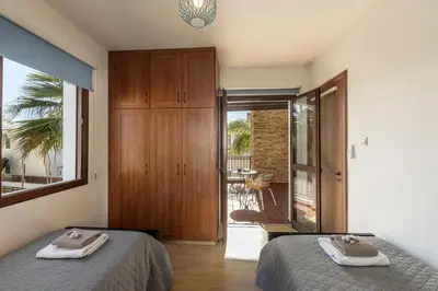 a bedroom with two beds and a sliding glass door at Villa Ionion 27 in Ayia Napa
