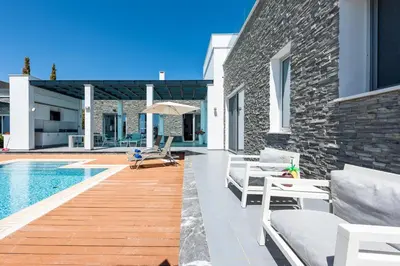 a backyard with a swimming pool and a house at Seafront Villa Maya by Ruidoso Luxury in Ayia Napa