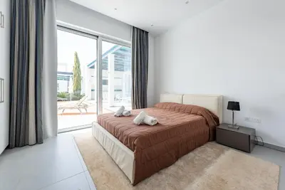 a bedroom with a bed and a large window at Seafront Villa Maya by Ruidoso Luxury in Ayia Napa