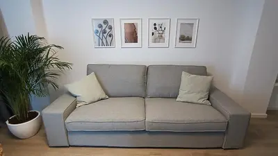 a grey couch in a living room with pictures on the wall at Sunorama Waterfront Apartment in Larnaka