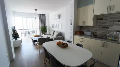 a kitchen and living room with a white table and chairs at Sunorama Waterfront Apartment in Larnaka