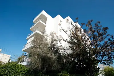 a white building with a tree in front of it at Glabur Stays - The Sunny Atelier - Nicosia City, Free Parking & Wifi, Welcomes You!!! in Nicosia