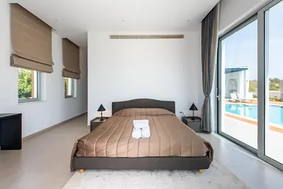 a bedroom with a large bed and a swimming pool at Seafront Villa Cecelia by Ruidoso Luxury in Ayia Napa