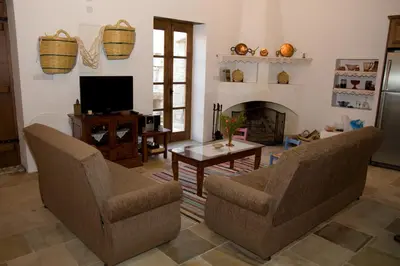 a living room with two chairs and a fireplace at Xenios Cottages in Lofou