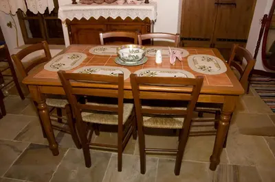 a dining room table and chairs with a table and plates and bowls at Xenios Cottages in Lofou