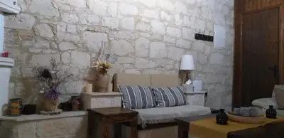 a living room with a couch and a stone wall at Magdalous House in Arsos