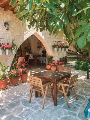 a wooden table and chairs in a courtyard with flowers at Magdalous House in Arsos