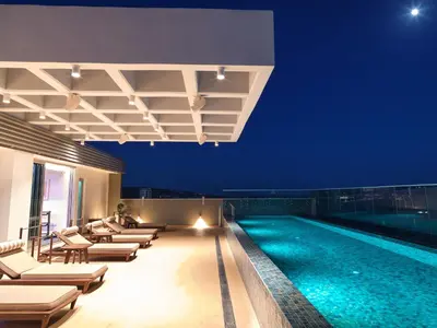a pool with chaise lounge chairs and a hotel at The Tower at St Raphael Resort in Limassol