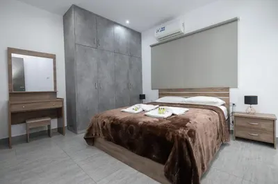 a bedroom with a bed and a dresser and a mirror at Bellagio Napa Suites in Ayia Napa