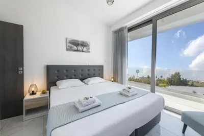 a bedroom with a large white bed and a large window at Protaras Royal Pearl Villa 7 in Protaras