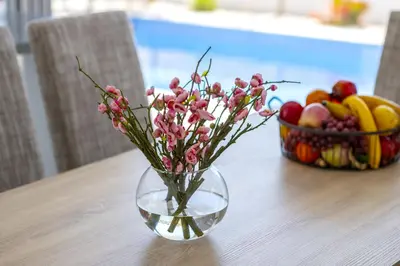 a vase with pink flowers sitting on a table with a bowl of fruit at Protaras Royal Pearl Villa 7 in Protaras