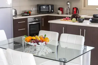 a kitchen with a glass table with a bowl of fruit at Protaras Palm Villa 54 in Protaras