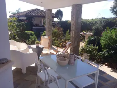 a patio with a table and white chairs and a house at Villa in Ayia Napa with a pool! in Ayia Napa