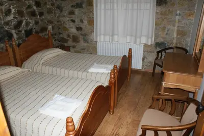 a bedroom with two beds and a table and chairs at ATRATSA Mountain Suites in Kalopanayiotis