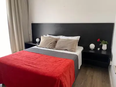 a bedroom with a large bed with a red blanket at A.V Central Apartment in Larnaka