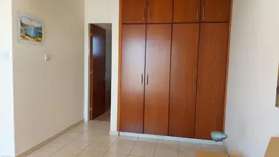 a hallway with wooden cabinets and a chair in a room at Nissi Golden Sands Lome in Ayia Napa