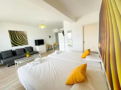 a bedroom with two beds and a living room at Lovely Studio Ayia Napa in Ayia Napa