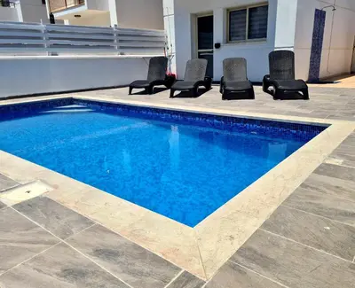 a swimming pool with chairs next to a house at KapparisVilla in Paralimni