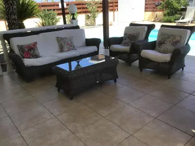 a patio with four chairs and a couch and a table at Carolyn Villa is a Luxury 4-Bedroom Villa with Private Pool in Ayia Napa in Ayia Napa