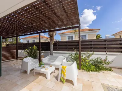 a patio with white furniture under a wooden pergola at Villa Eftihia in Protaras