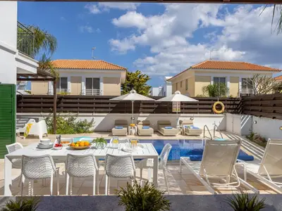 a patio with a table and chairs next to a pool at Villa Eftihia in Protaras