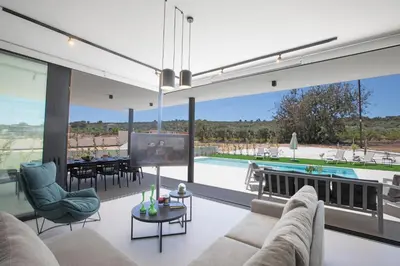 a living room with a couch and a tv and a pool at Elite Pearl Villas in Protaras