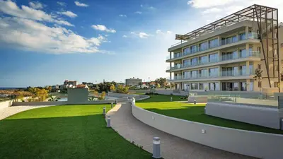 a building with a green lawn in front of it at Emerald Suites in Protaras