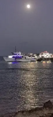 a boat in the water at night with a full moon at KSQUARED in Protaras