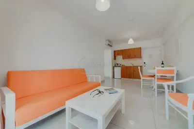 a living room with an orange couch and a table at Christos Napa Self Serviced Apartments in Ayia Napa