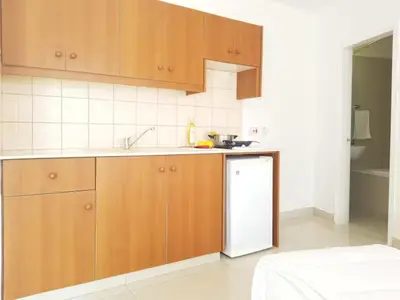 a kitchen with wooden cabinets and a white refrigerator at Christos Napa Self Serviced Apartments in Ayia Napa