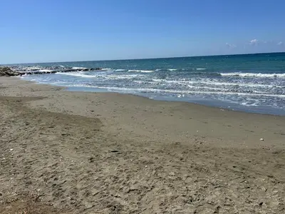 a sandy beach with waves in the ocean at Mersey Faros Complex in Pervolia