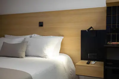 a bed with white pillows and a wooden head board at Alinea Urban Saripolou Square in Limassol