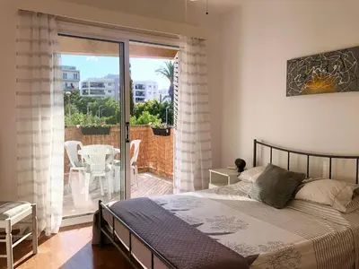 a bedroom with a bed and a balcony with a table at 1 bedroom flat, prime location near sea, sleeps 4 in Limassol