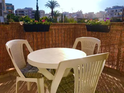 a white table and chairs on a balcony with flowers at 1 bedroom flat, prime location near sea, sleeps 4 in Limassol