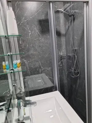 a bathroom with a shower with a glass door at Kamaroporta Luxury Apartments in Ayios Theodhoros