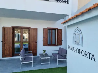 a patio with chairs and a table next to a building at Kamaroporta Luxury Apartments in Ayios Theodhoros