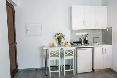 a kitchen with white cabinets and a table with flowers at Kamaroporta Luxury Apartments in Ayios Theodhoros