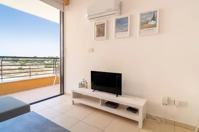 a living room with a flat screen tv on a white wall at Mirabella Mackenzie 1 Bedroom Flat Near the Sea in Larnaka