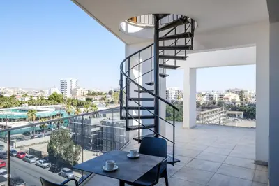 a spiral staircase in a building with a table and chairs at Solaar Apartments st Lazarous in Larnaka