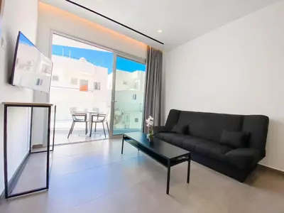 a living room with a black couch and a table at Caramela Luxury Apts in Ayia Napa