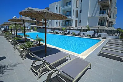 a swimming pool with lounge chairs and umbrellas at Golden Tree Apartment in Paralimni