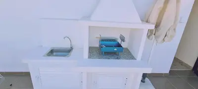 a white kitchen with a sink and a blue stool at STAY Trinity Beach Apts in Paralimni