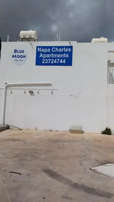 a white building with a blue sign on it at Napa Charles Apts in Ayia Napa