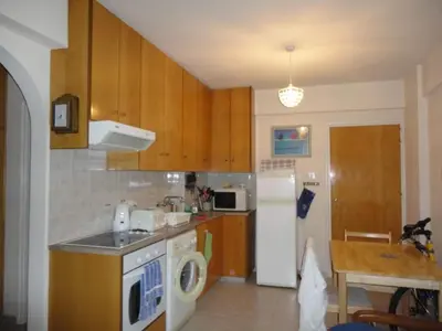 a kitchen with wooden cabinets and a white refrigerator at Apartments Mackenzie 1+1 in Larnaka