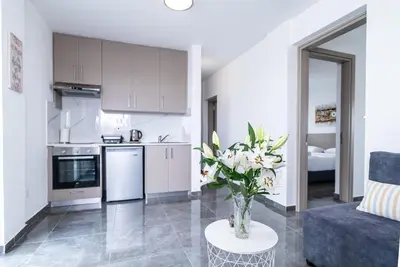 a kitchen and living room with a vase of flowers on a table at Spiros Luxury Apartments in Ayia Napa