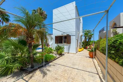 a walkway in front of a building with palm trees at Protaras Villa Elena 3 in Protaras